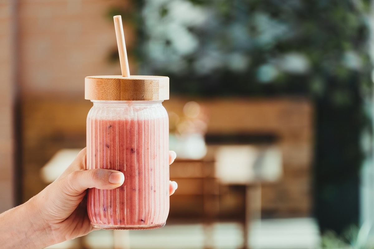 Young woman\'s hand with a red fruit smoothie.