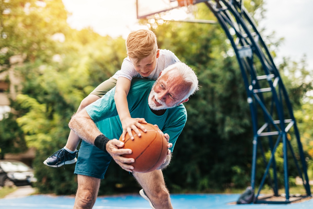 Grandfather and his grandson enjoying and playing together on basketball court.